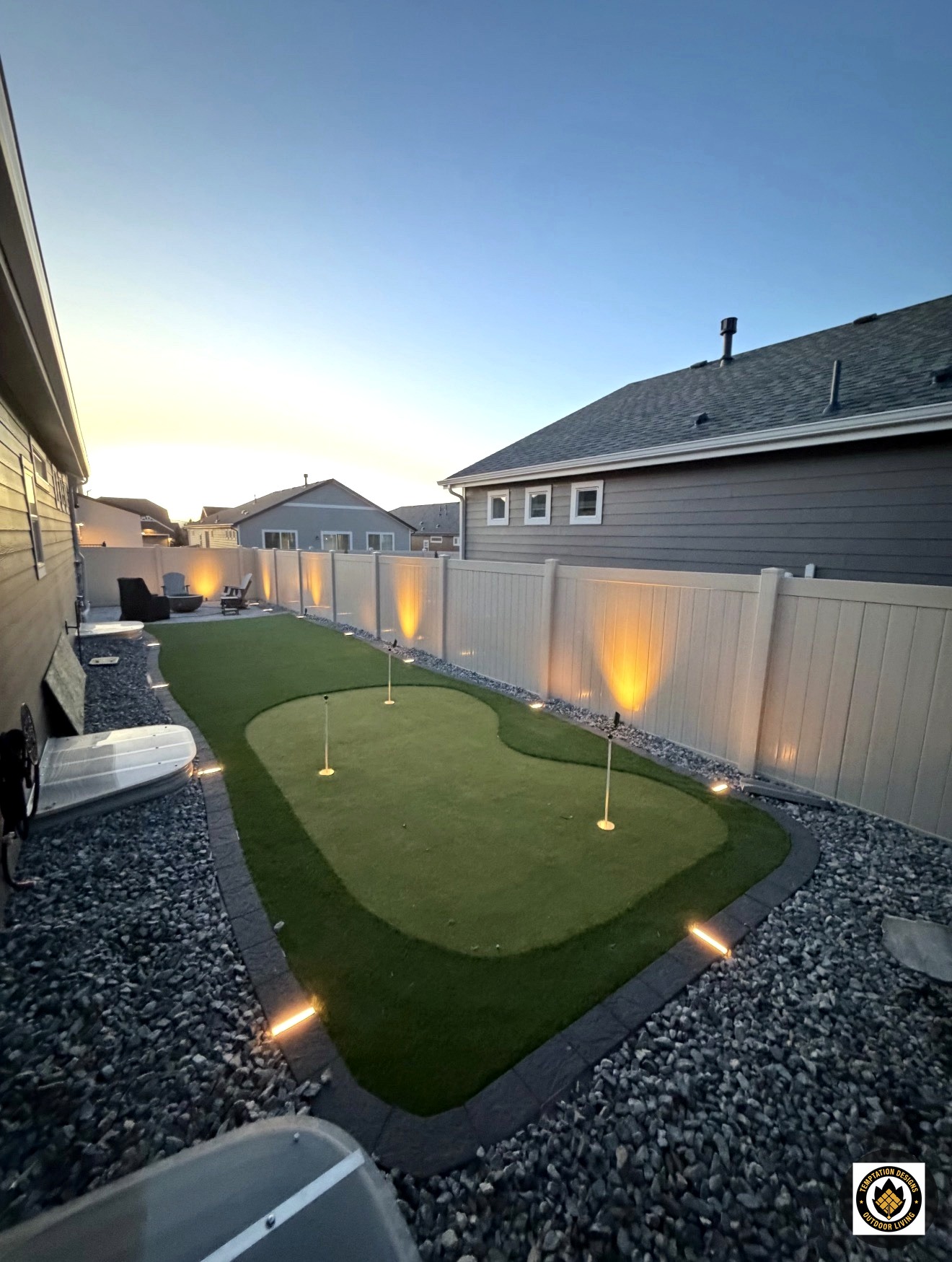 Backyard putting green at dusk with landscape lighting