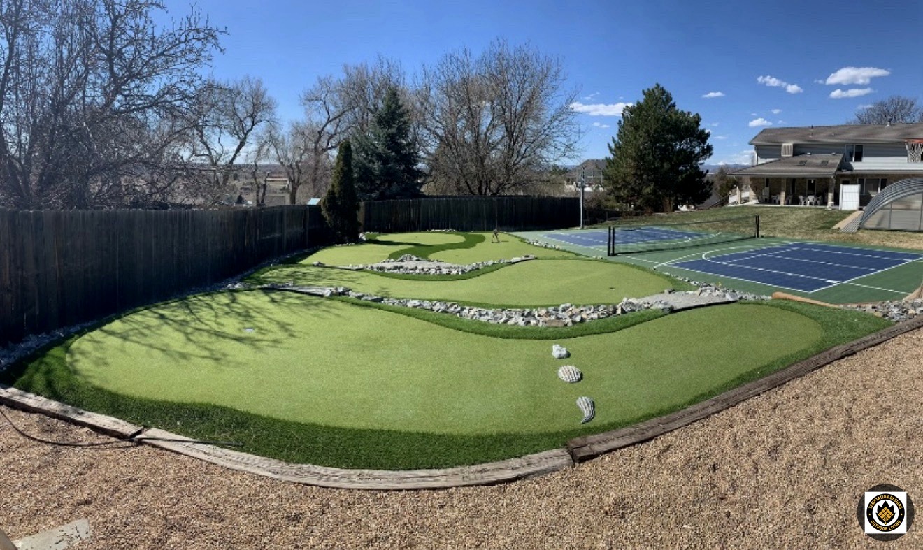Backyard putting green next to a sport court
