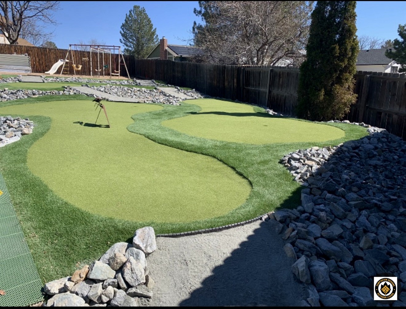 Backyard putting green edged with decorative rocks