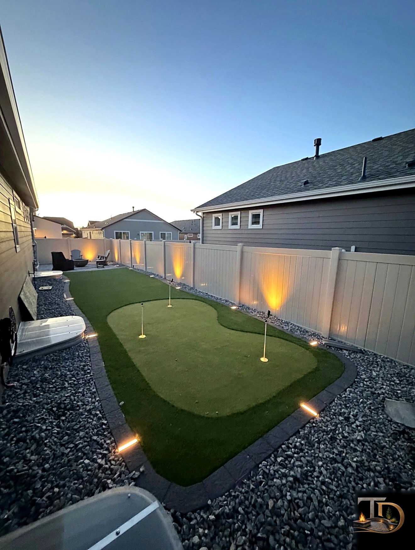 Backyard putting green at dusk with landscape lighting