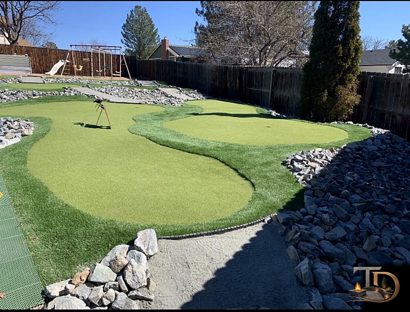 Backyard putting green edged with decorative rocks