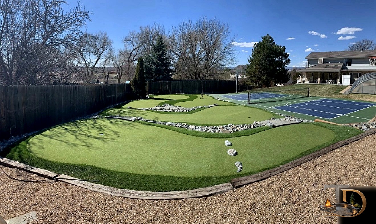 Backyard putting green next to a sport court